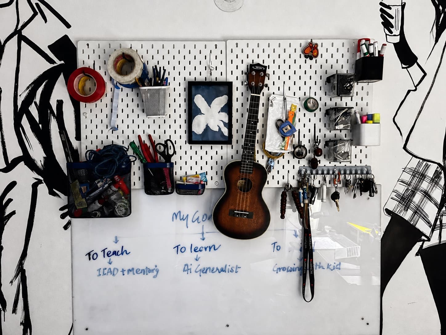Pegboard and whiteboard on the studio wall, with a ukulele, tools, and handwritten goals.